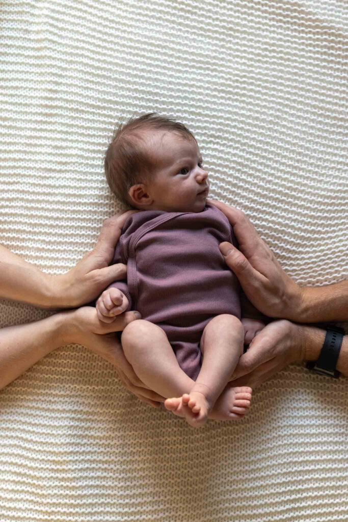 baby blir holdt av to par hender