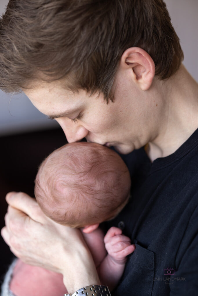 Far holder babyen sin og kysser ham på hodet. livsstilsfotograf 