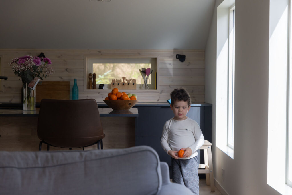 Når barn ikke samarbeider på familiefoto – slik foregår familiefotografering i Bergen når barna får være seg selv. Bilde av en liten gutt hjemme hos seg selv i stuen sin. 