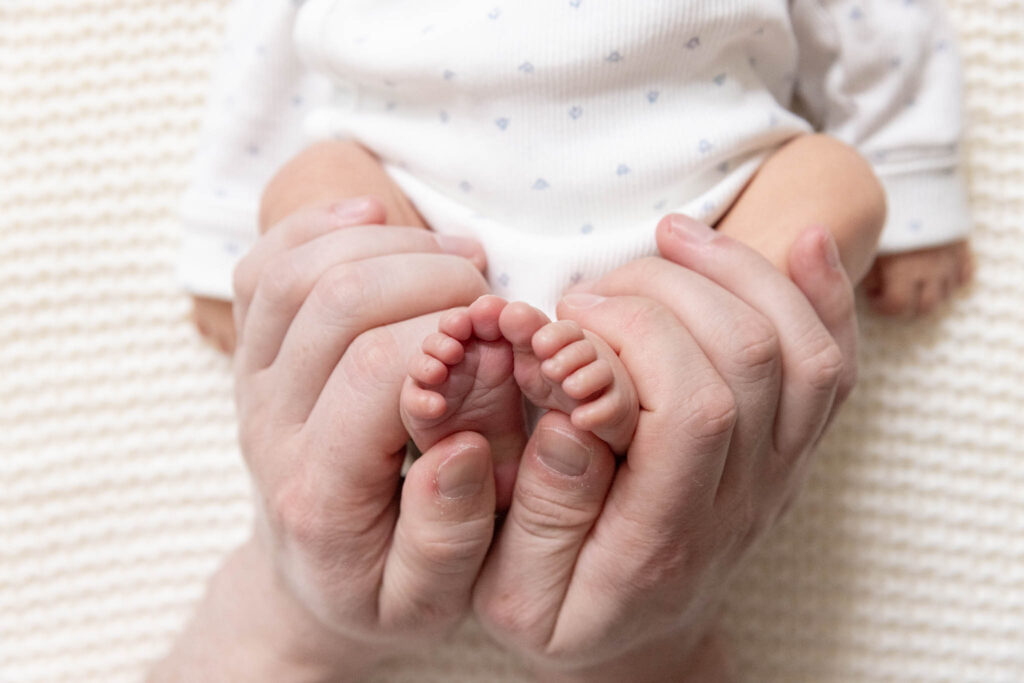 hender som holder rundt babyføtter. 