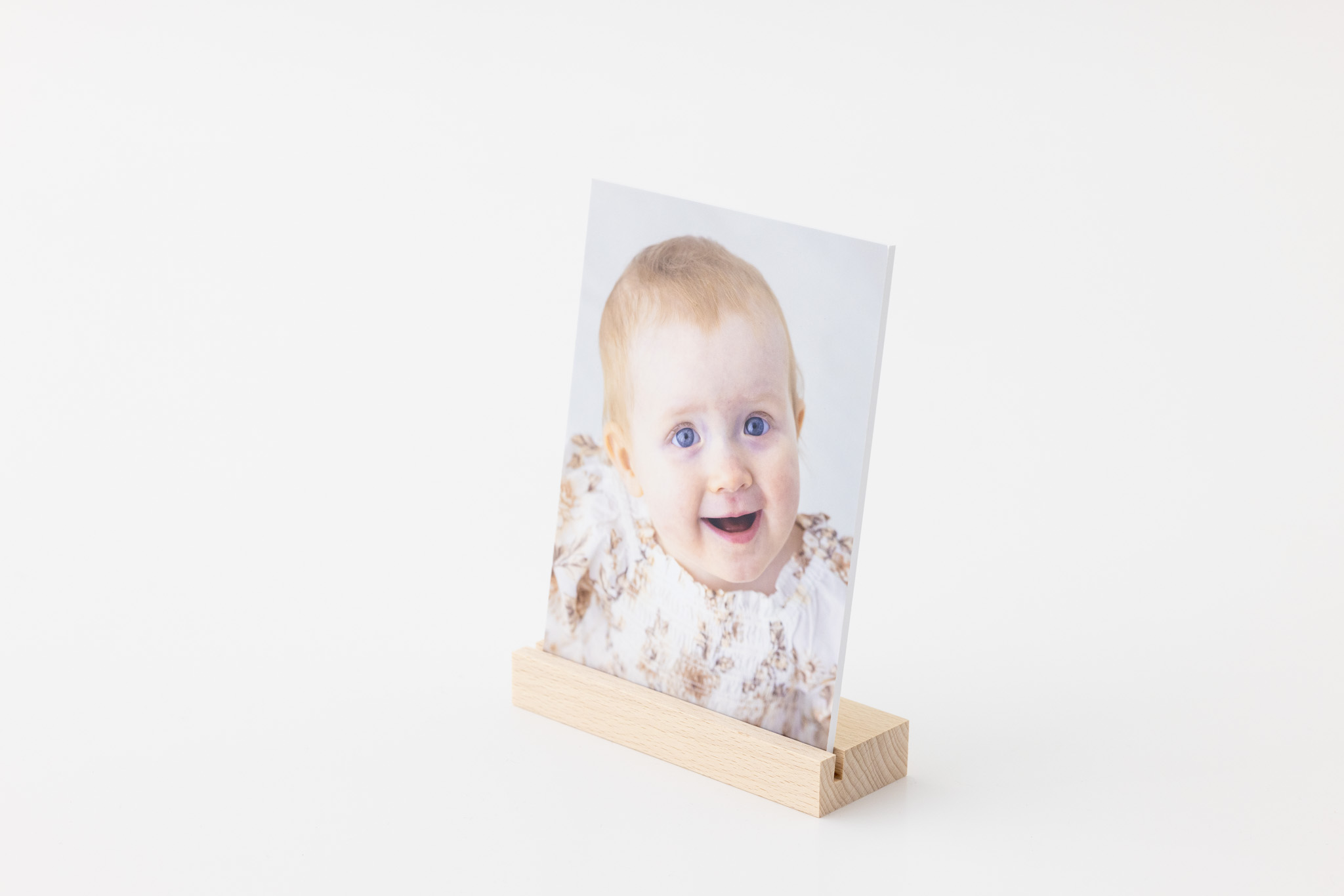 Bilder i hverdagen. Laminert bilde av en ettåring som ser mot kamera, plassert i trekloss.